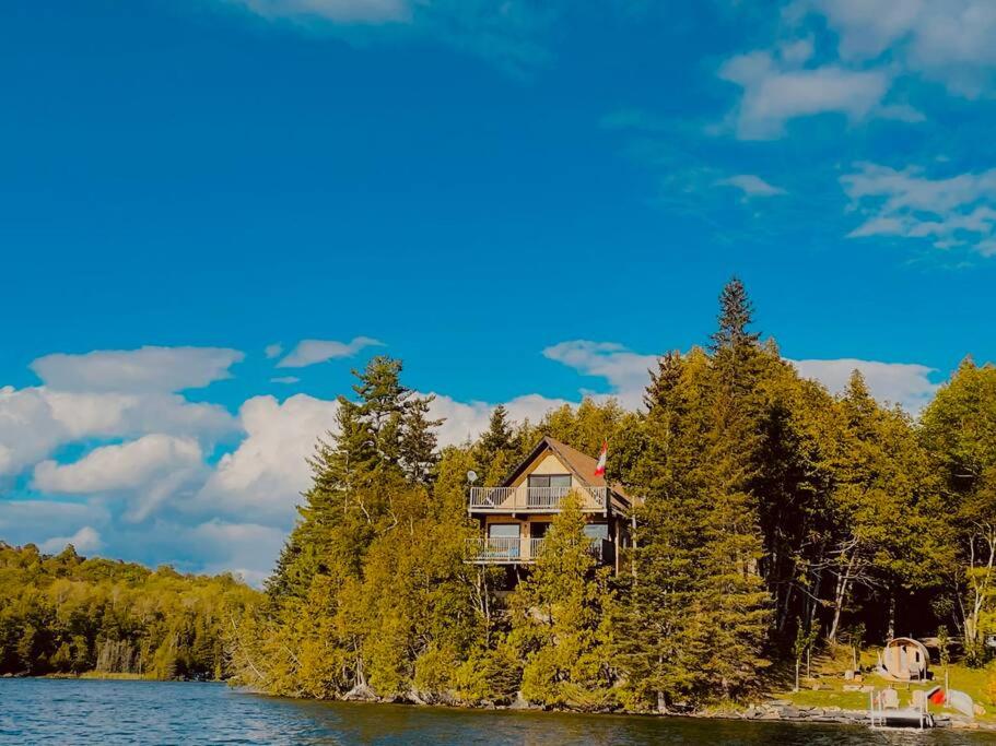 a house on an island in the middle of a lake at Four Season Cottage with Wood Burning Sauna in Ompah