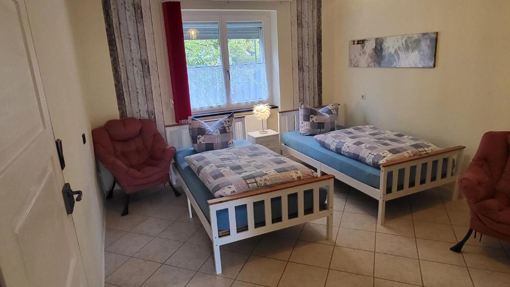 a room with two beds and two chairs and a window at Haus Adelheid in Weil am Rhein