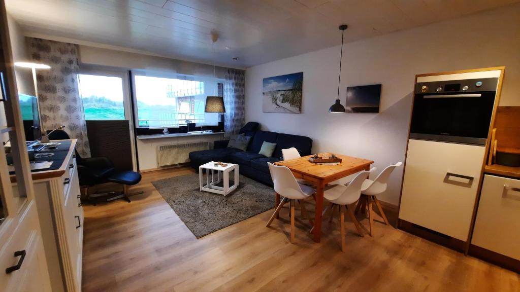 a kitchen and living room with a table and a couch at Fewo Am Deich 1 Appartment 30 in Sankt Peter-Ording