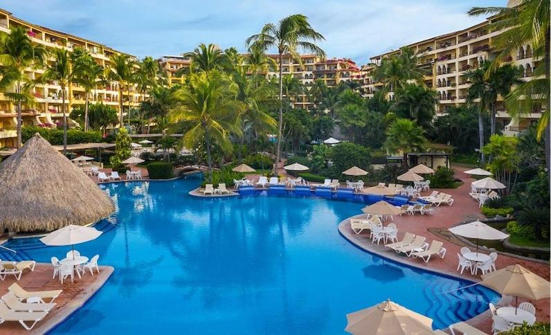 a resort swimming pool with chairs and umbrellas at Oceanview Condo Vela Vallarta condo in Puerto Vallarta