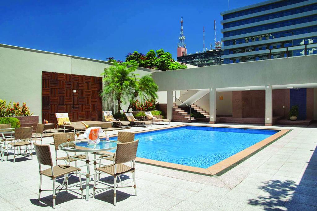 un patio con piscina, tavolo e sedie di Windsor Plaza Brasilia a Brasilia