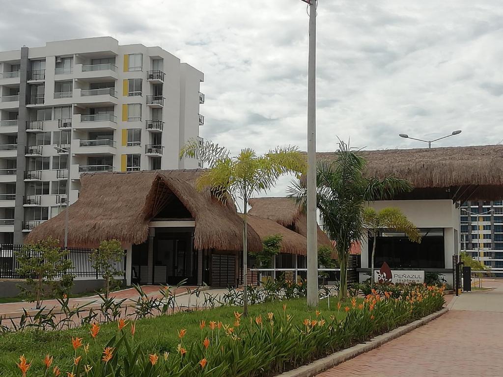 een gebouw met een rieten dak en een hoog gebouw bij Apartamento en Ricaurte, via a Girardot Relajación Garantizada in Ricaurte