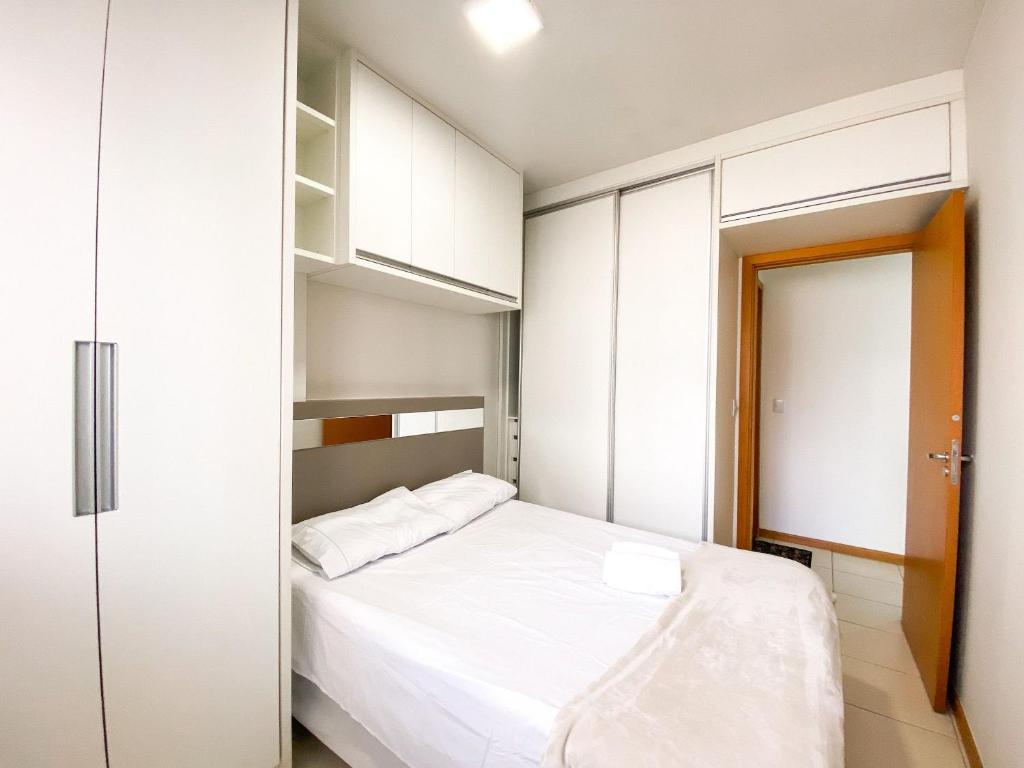 a small bedroom with a white bed and white cabinets at Ao lado do Metrô e Shopping (1Qto) in Brasilia