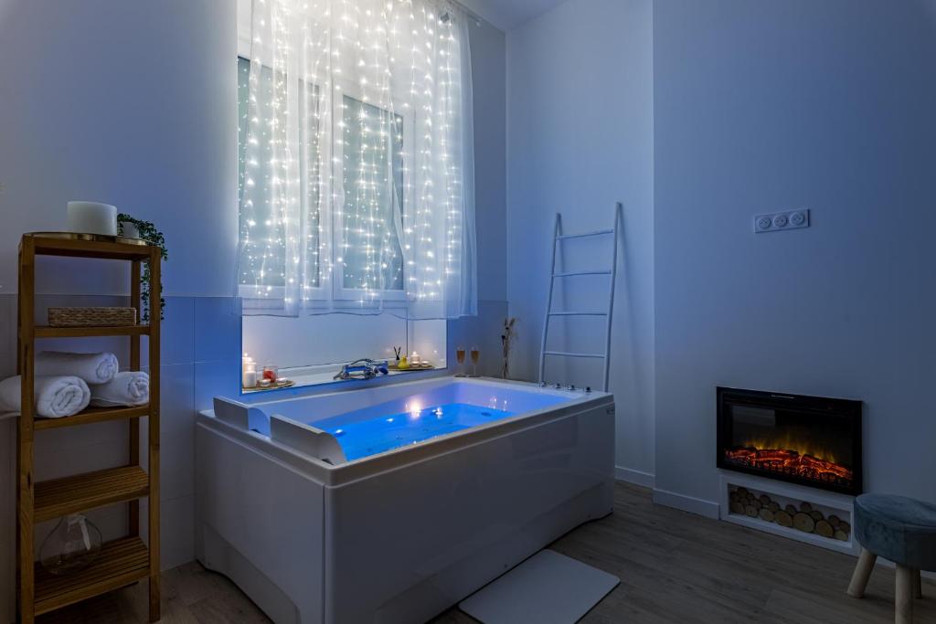 a bathroom with a large tub with a fireplace at Suite Évasion Céleste Balnéo et Ciné proche Zénith in Saint-Étienne