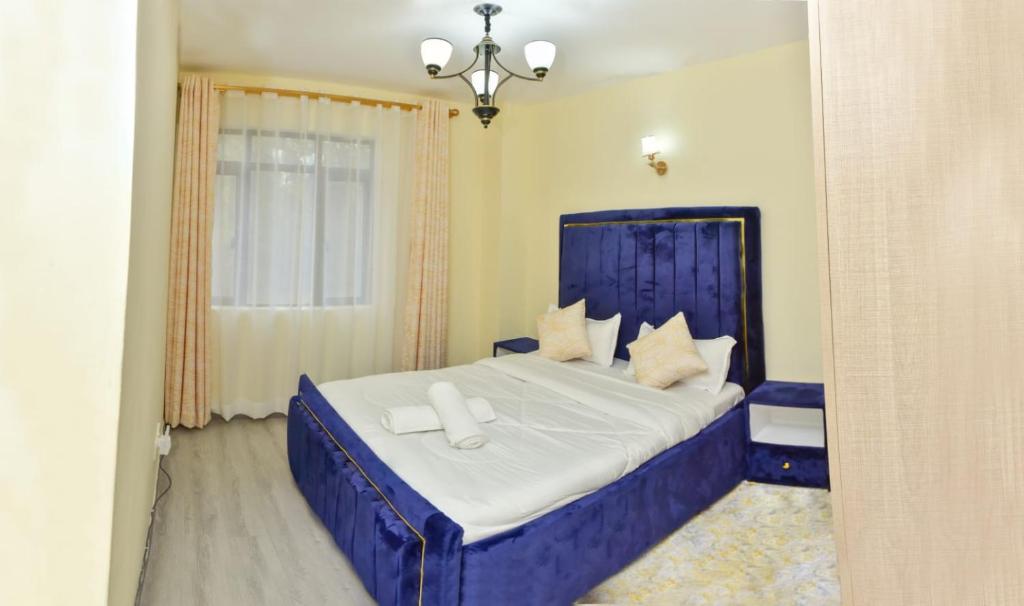 ein Schlafzimmer mit einem blauen Bett mit weißer Bettwäsche und Kissen in der Unterkunft Sandalwood Garden in Nairobi