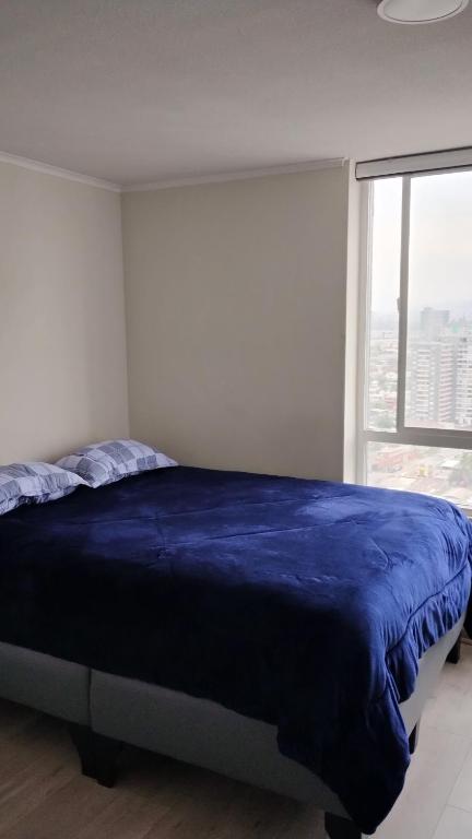 a bedroom with a blue bed with a large window at Edificio Núcleo espectacular departamento in Santiago