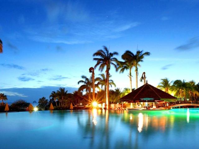 - une grande piscine d'eau bordée de palmiers la nuit dans l'établissement TI OASIS Studio vue Mer dans village Pierre & Vacances, à Sainte-Luce