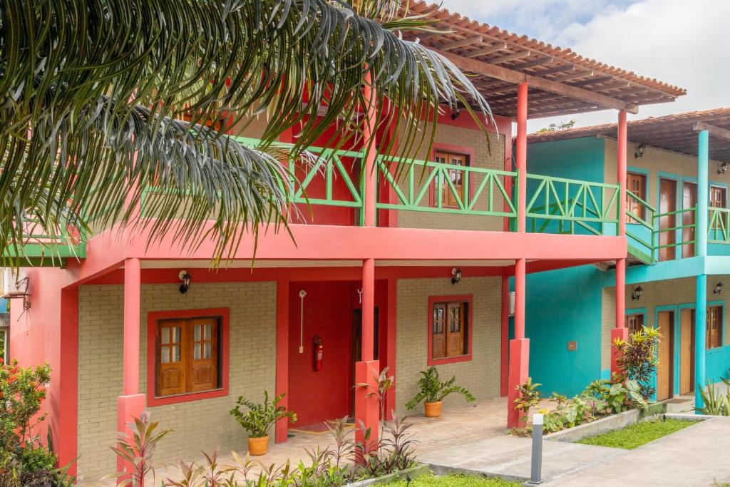 a colorful house with a palm tree in front of it at POUSADA CAJUEIRO in Santo Amaro