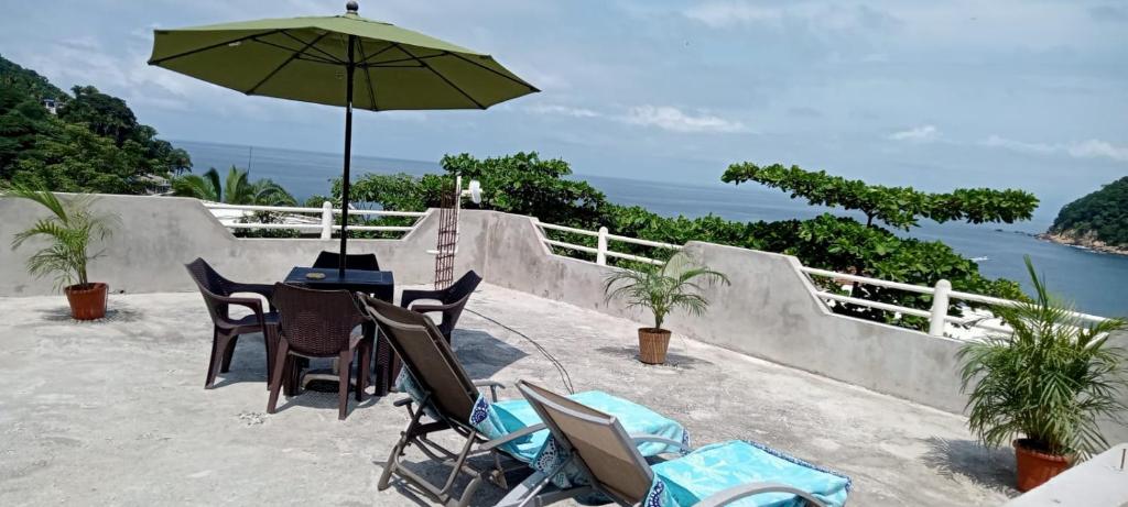 een tafel en stoelen met een parasol op een patio bij Casa SanMar cerca de la playa in Yelapa