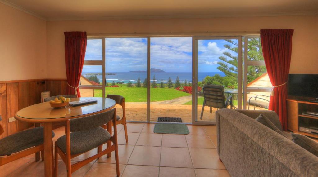 uma sala de estar com uma mesa e cadeiras e uma grande janela em Islander Lodge Apartments em Burnt Pine