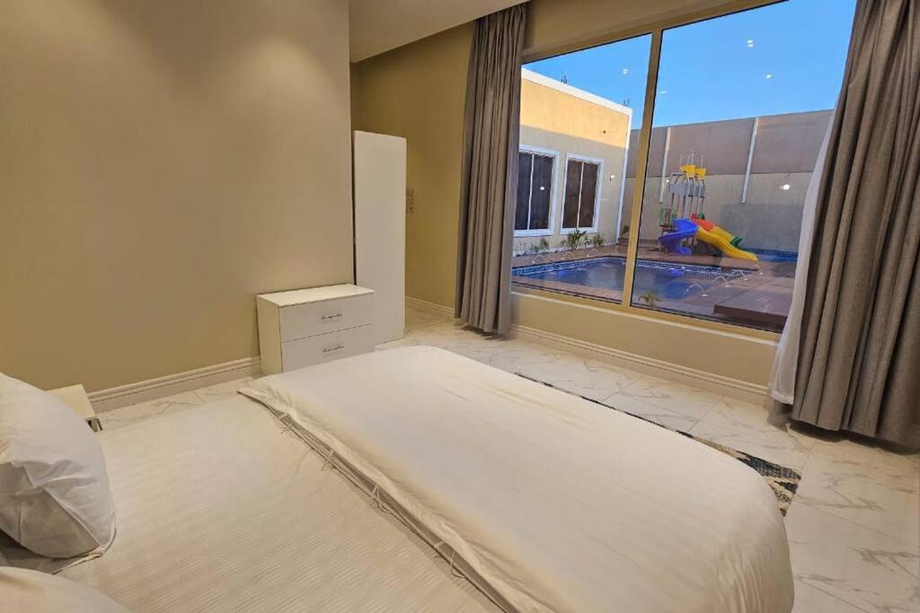 a bedroom with a large bed and a large window at شالية بيهاتش in Al-Salam