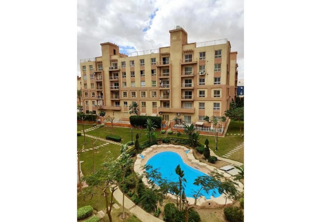 a building with a pool in front of it at A Wonderful Apartment in a compound in October Gardens in ‘Ezbet `Abd el-Ḥamîd