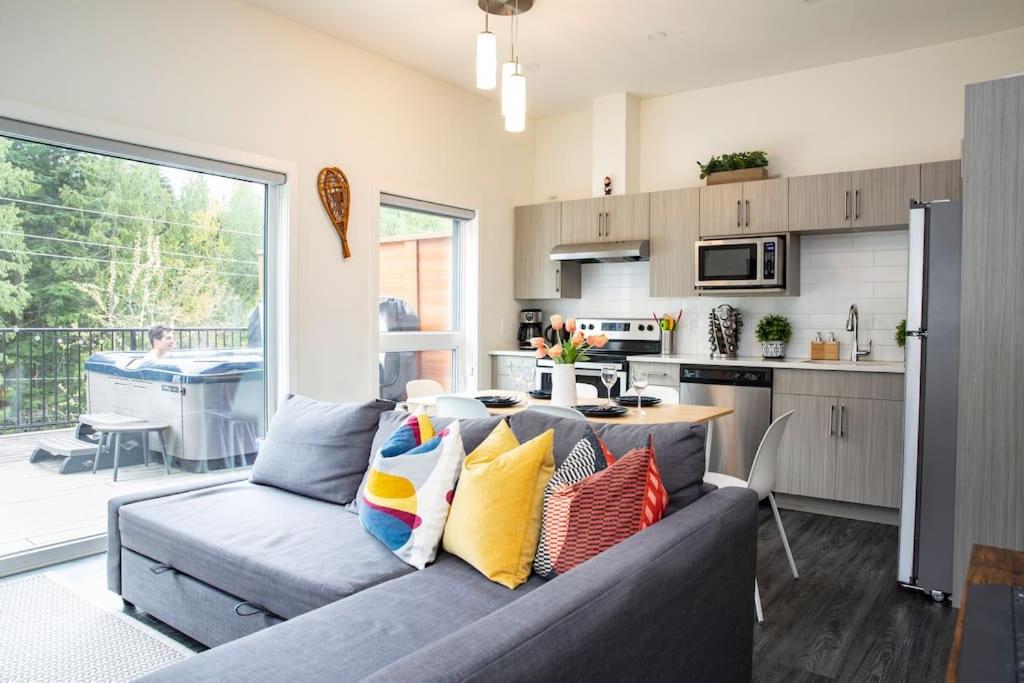 a living room with a gray couch with colorful pillows at Reved Up & Out - Remarkable Two Bedroom Condo in Revelstoke