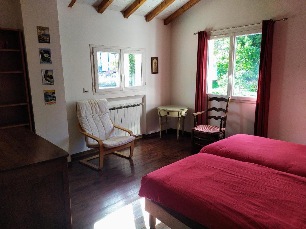 - une chambre avec un lit rouge et une chaise dans l'établissement XOKO GORRI, à Urrugne