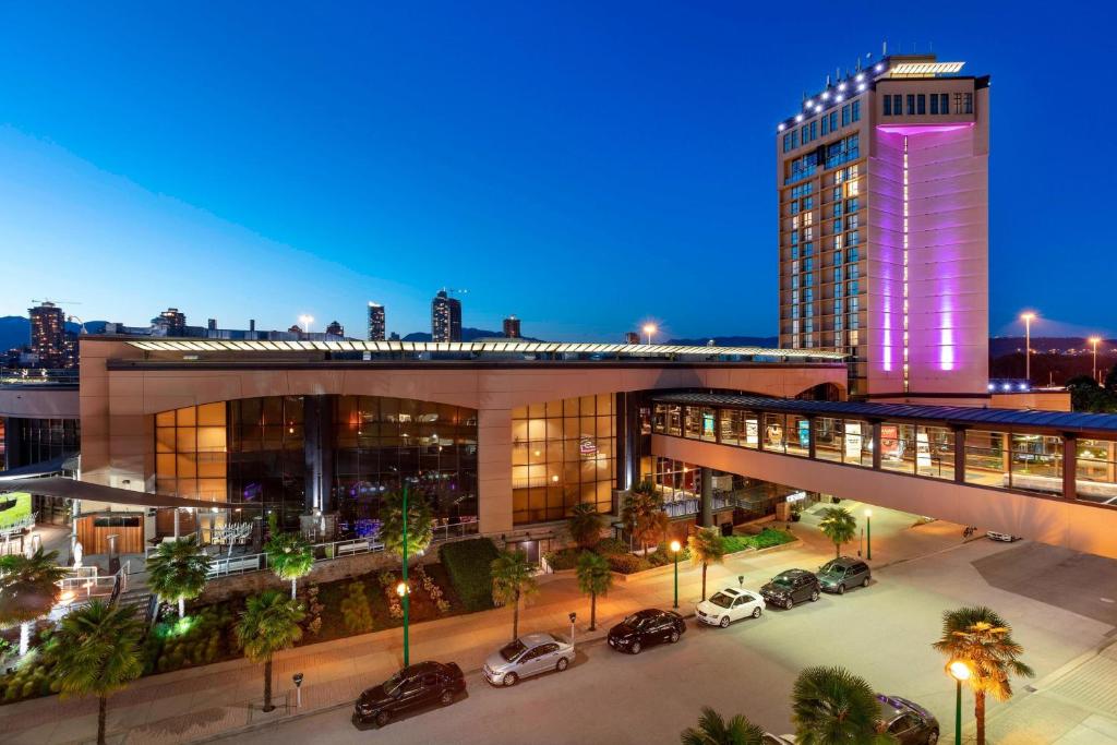 duży budynek z samochodami zaparkowanymi na parkingu w obiekcie Delta Hotels by Marriott Burnaby Conference Centre w mieście Burnaby