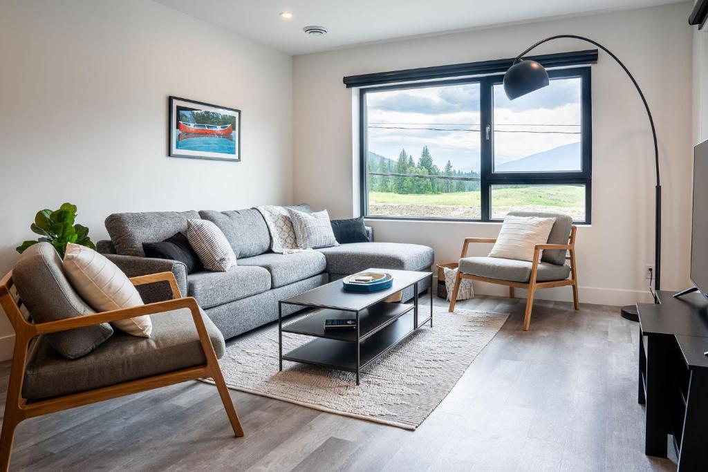 a living room with a couch and chairs and a window at Revy's Peak Condo - Hot Tub with View in Revelstoke