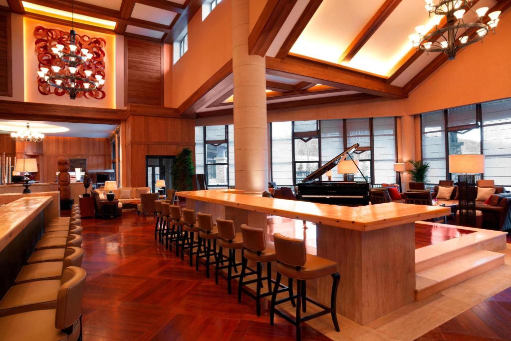 a lobby with a bar with chairs and a piano at Sheraton Changbaishan Resort in Fusong