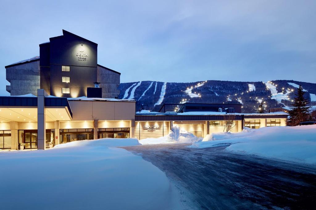 a building with a clock on it in the snow at Delta Hotels by Marriott Mont Sainte-Anne, Resort & Convention Center in Beaupré