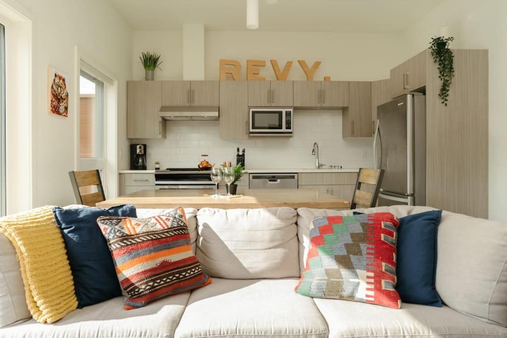 uma sala de estar com um sofá branco e uma cozinha em The Nest - Condo with Hot Tub & BBQ em Revelstoke