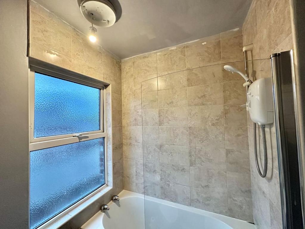 baño con bañera y ventana en Perfect Group/Contractors Home en Barnsley