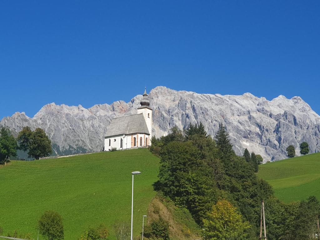a church on a hill with a mountain in the background at Emma Top 2 in Dienten am Hochkönig