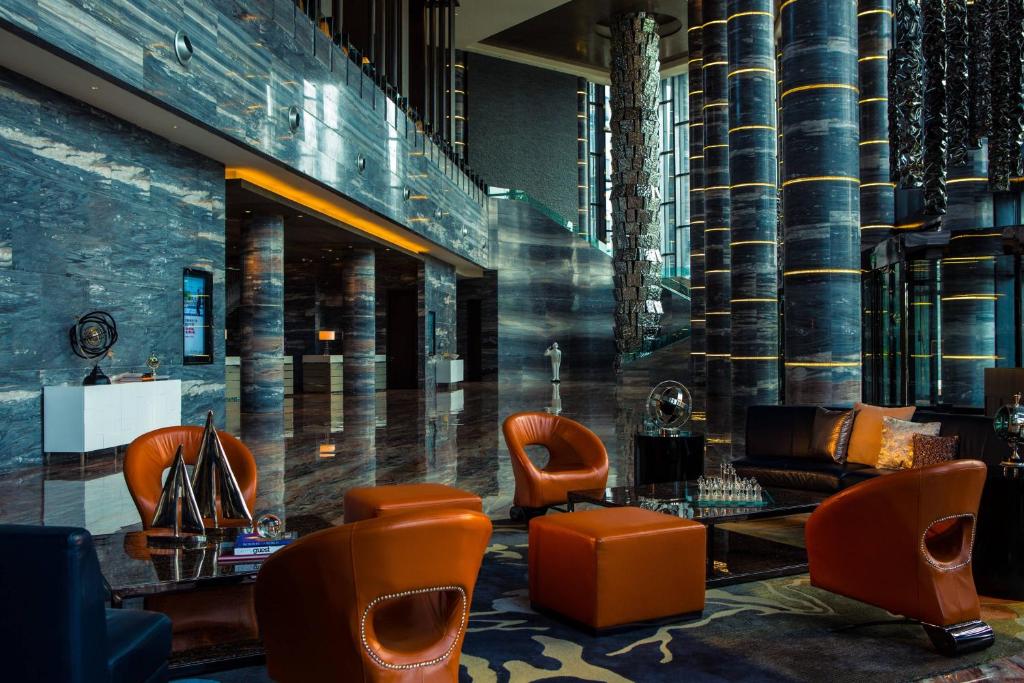 eine Lobby mit orangefarbenen Stühlen und einer Couch in der Unterkunft Renaissance Guiyang Hotel in Guiyang