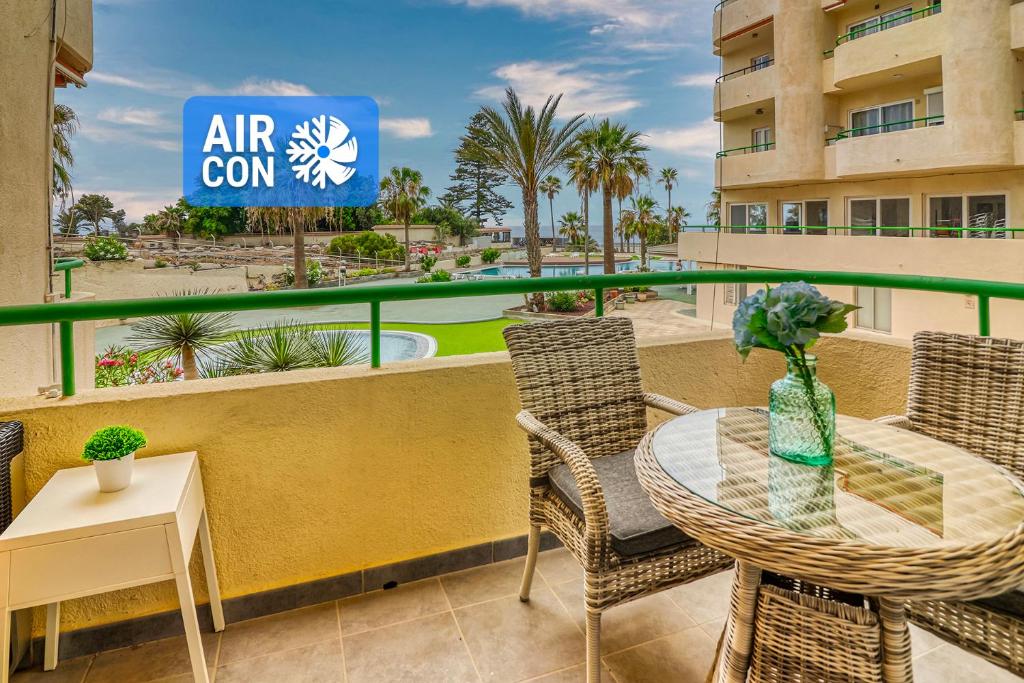 a balcony with a table and chairs and a sign that reads air con at Modern apartment with an addictive terrace view in Los Cristianos