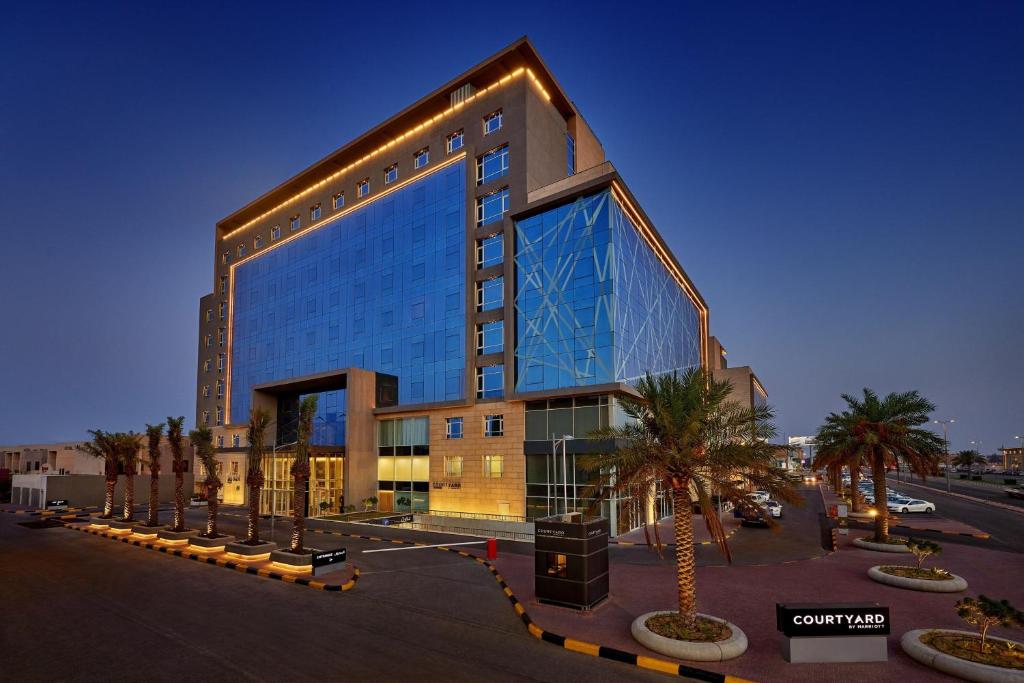 a large glass building with palm trees in front of it at Courtyard by Marriott Jubail in Al Jubail