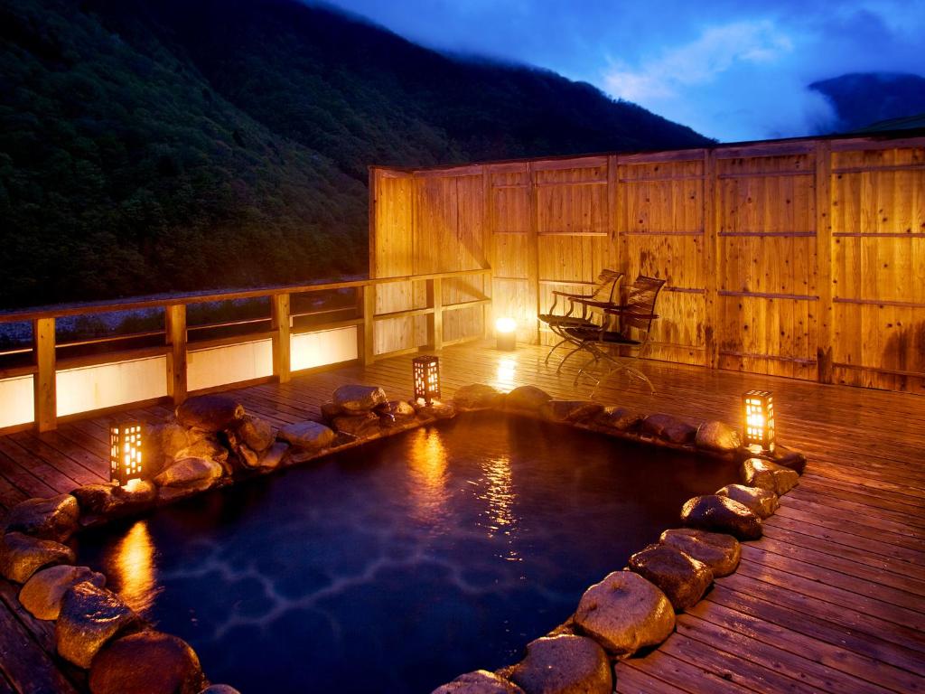 uma piscina de água num deque de madeira à noite em Yukimurasaki em Takayama