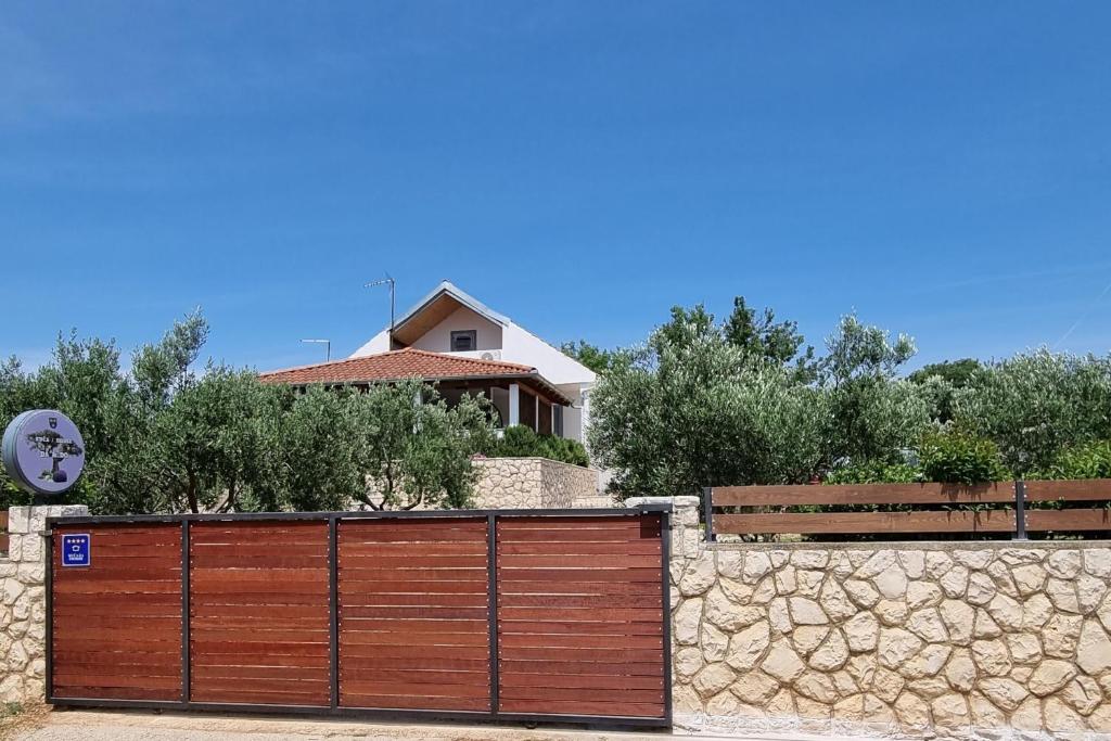 une clôture en bois devant une maison dans l'établissement Family friendly house with a swimming pool Vrana, Biograd - 21875, à Pakoštane