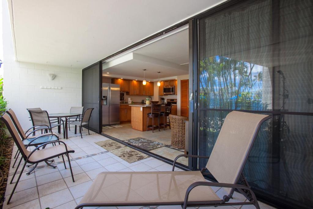balcón con sillas y mesa y cocina en Maui Parkshore 105 - MCH, en Kihei
