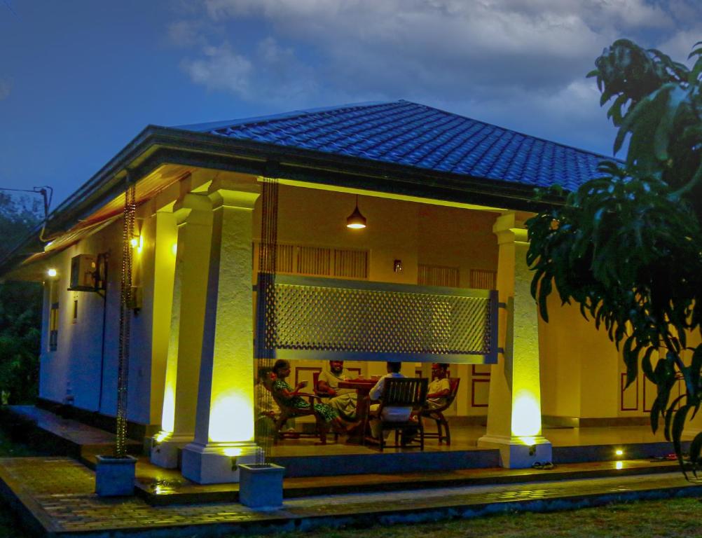 a house with people sitting on the porch at night at Serenity Villa Anuradhapura in Anuradhapura