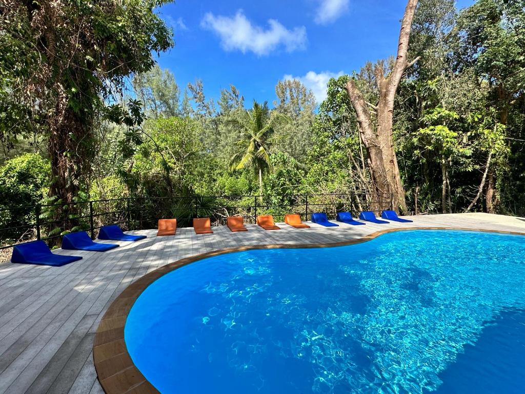 a swimming pool with blue lounge chairs and trees at Blanco Hostel Lanta in Ko Lanta