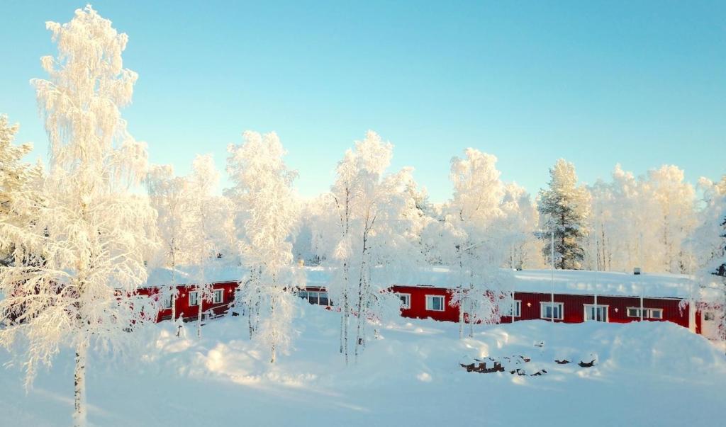 een rood gebouw bedekt met sneeuw met bomen bij Palojärven Lomakeskus in Sonka