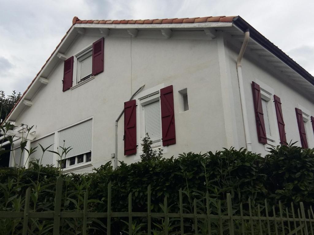 una casa blanca con persianas rojas y una valla en Appartement Lamalou-les-Bains, 2 pièces, 2 personnes - FR-1-451-37, en Lamalou-les-Bains