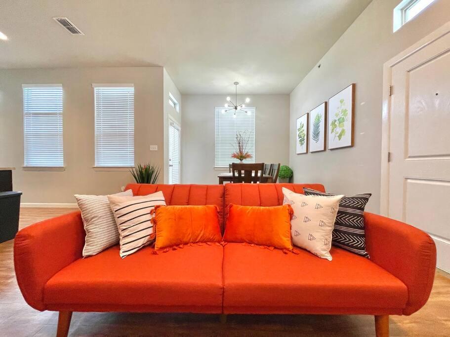 an orange couch with pillows on it in a living room at NEW! Luxury Apt, 5 min from Mall, Airport, & Dine! in McAllen