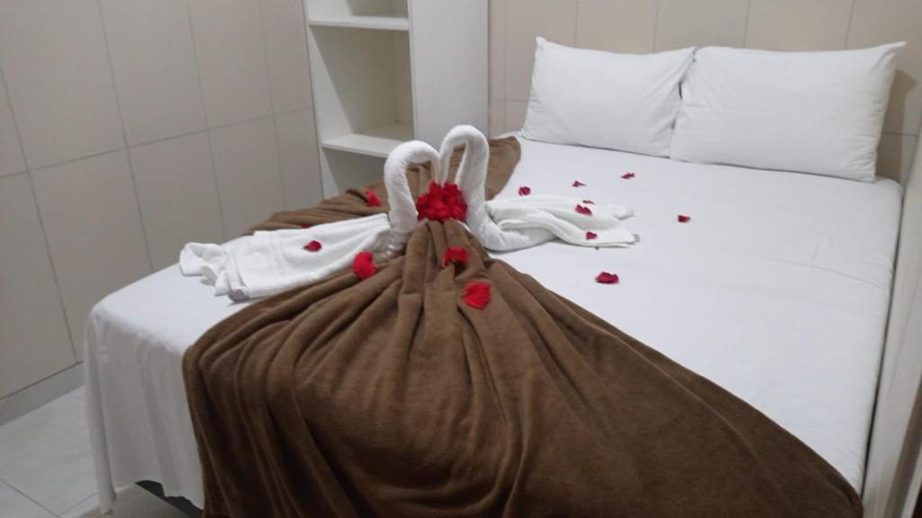 Una cama blanca con una manta con rosas. en Mini suíte Atitude Maragogi Centro en Maragogi