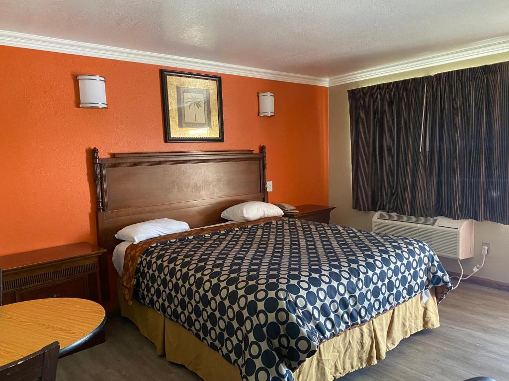 a hotel room with a bed with an orange wall at Downtown Motel 7 in San Bernardino