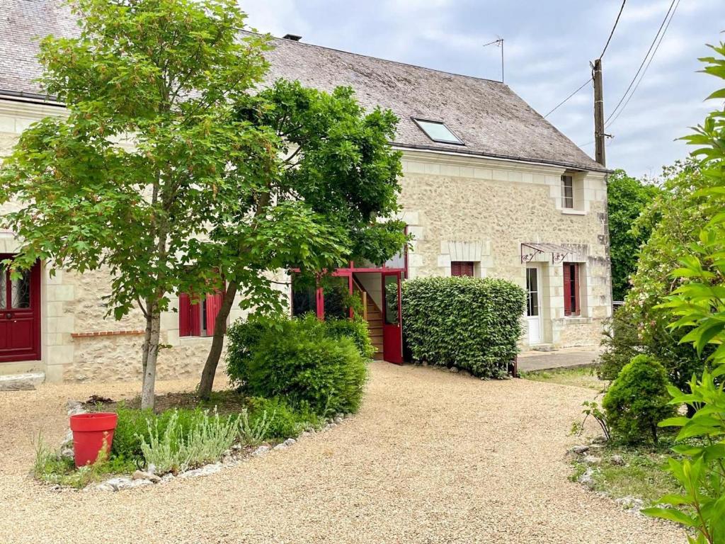 a stone house with red doors and a tree at Gîte à Luzillé avec jardin privé et climatisation - FR-1-381-532 in Luzillé