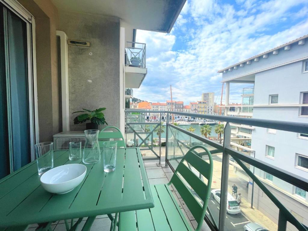- un balcon avec une table verte et un bol dans l'établissement Joli T2 climatisé proche centre avec parking privé et loggia - Sète - FR-1-338-544, à Sète