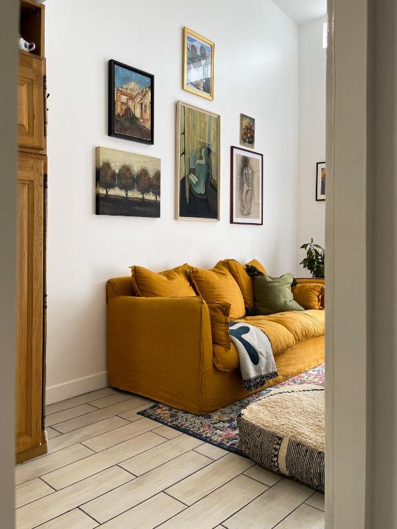 um sofá amarelo numa sala de estar com fotografias na parede em Tiny house 15min away from Opera Garnier em Argenteuil