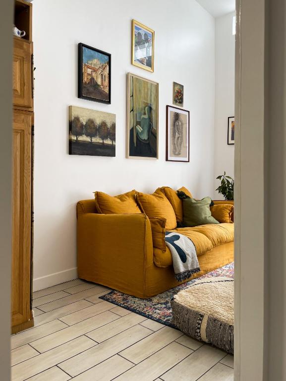 a yellow couch in a living room with pictures on the wall at Tiny house 15min away from Opera Garnier in Argenteuil