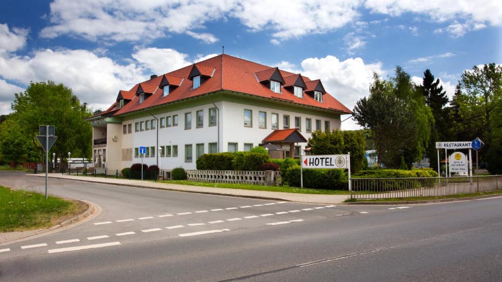 un grand bâtiment blanc avec un toit rouge dans une rue dans l'établissement Hotel am Stadtpark Nordhausen, à Nordhausen