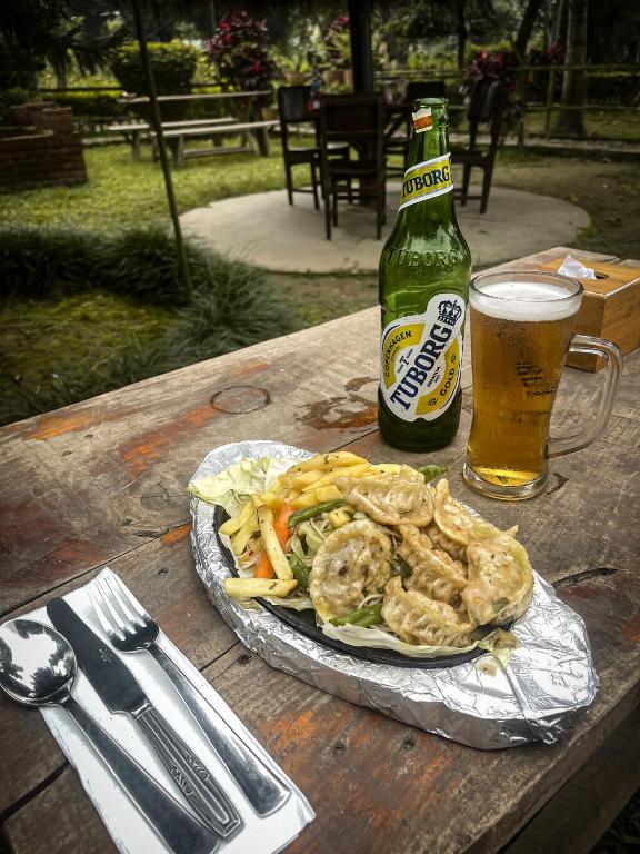 a table with a plate of food and a bottle of beer at Hotel Tharu Garden And Beer Bar in Chitwan