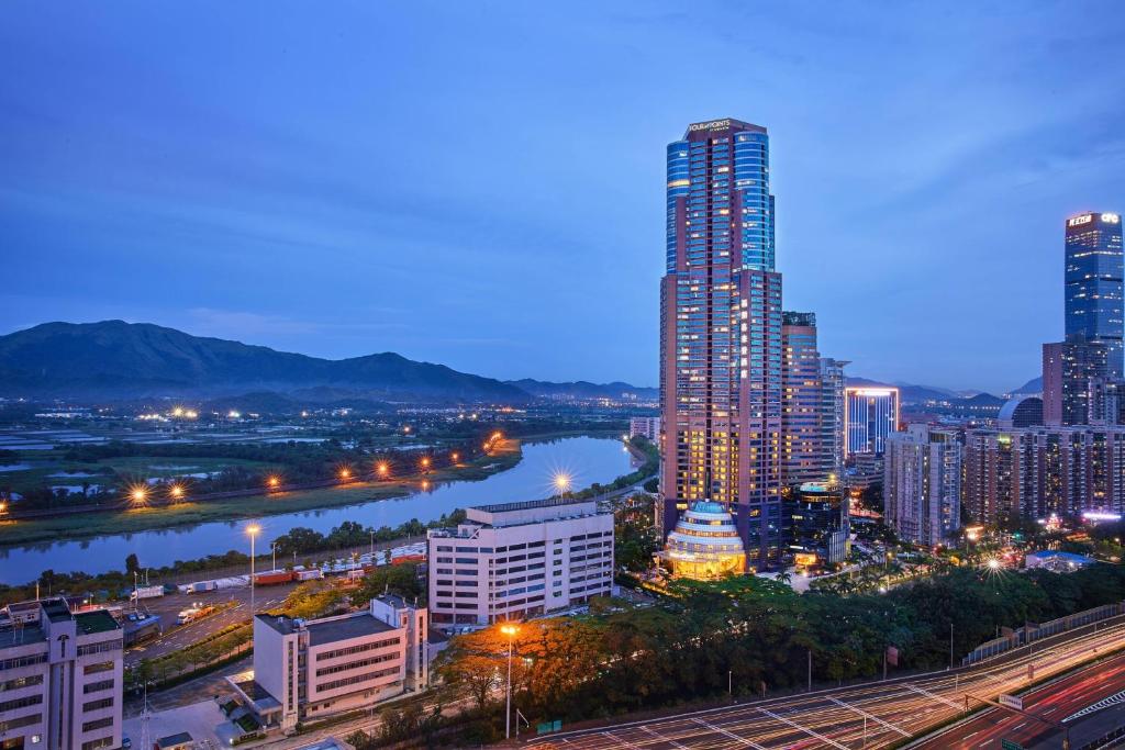 Four Points by Sheraton Shenzhen في شنجن: أفق المدينة في الليل مع مبنى طويل