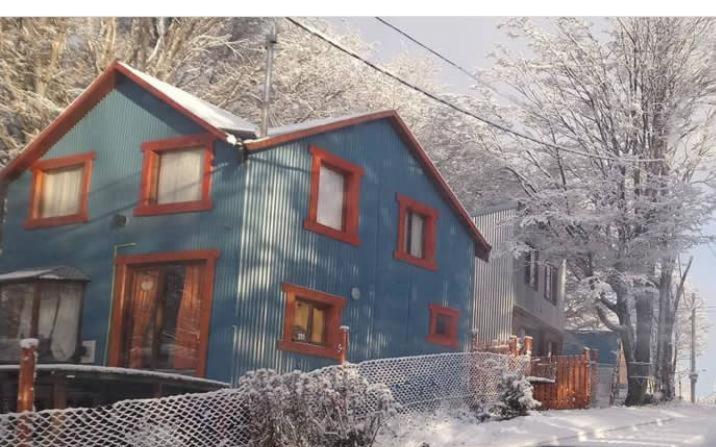 une maison bleue avec des fenêtres rouges dans la neige dans l'établissement Dream Landscape, à Ushuaia