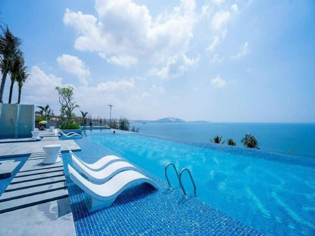 a swimming pool with a view of the ocean at Apec Mandala Mũi Né Condotel in Mui Ne