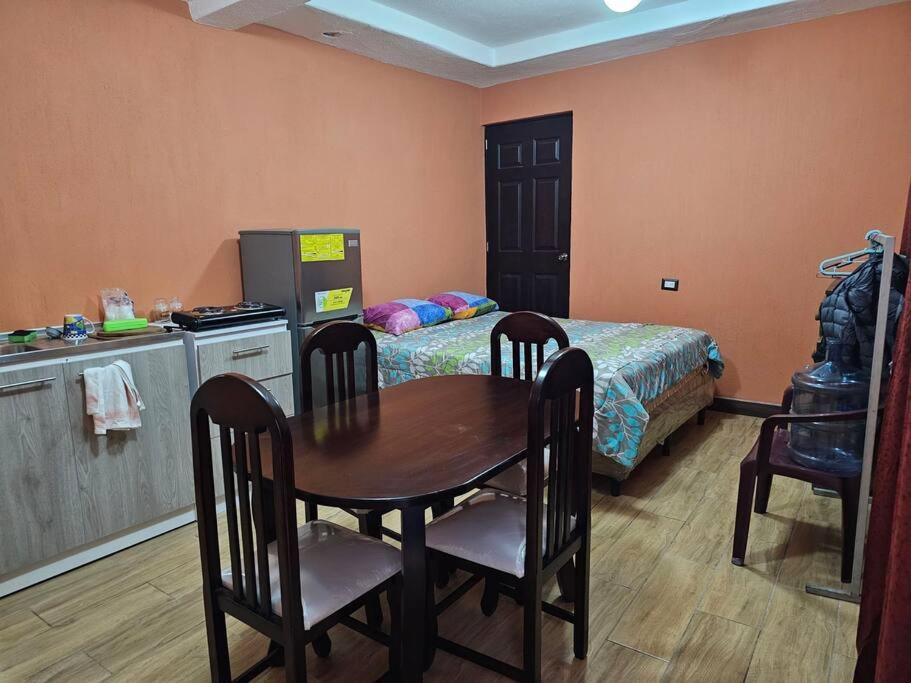 um quarto com uma mesa, uma cama e uma cozinha em Apartamento acogedor em Quetzaltenango