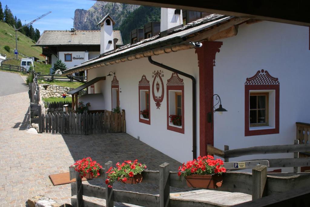 a small white building with flowers on the side at Agriturismo Maso Larciunei in Selva di Val Gardena
