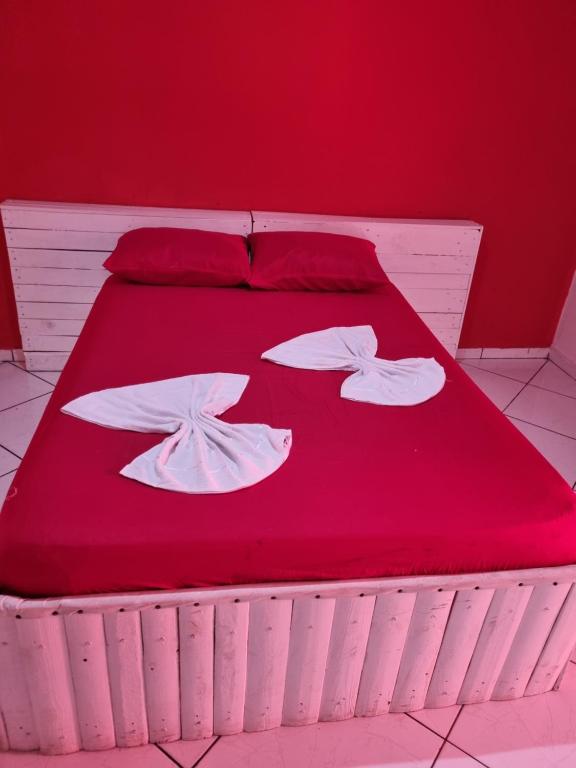 Una cama roja con dos almohadas blancas. en Pousada Lances De Amor, en Sorocaba